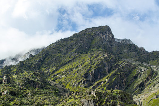 View of steep mountain slopes covered in green grass and rocky outcrops under a cloudy sky in Chilas Gilgit Pakistan. View of steep mountain slopes covered in green grass and rocky outcrops under a cloudy sky in Chilas Gilgit Pakistan.
