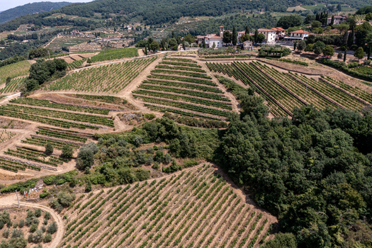 Aerial view of terraced vineyards on rolling hills with a small village and lush green forests Greve in Chianti Tuscany Italy. Aerial view of terraced vineyards on rolling hills with a small village and lush green forests Greve in Chianti Tuscany Italy.