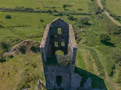 Aerial view of the historic stone ruins of a mine engine house surrounded by green fields and rolling hills in Minions Cornwall United Kingdom. Aerial view of the historic stone ruins of a mine engine house surrounded by green fields and rolling hills in Minions Cornwall United Kingdom.