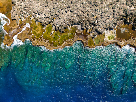 Aerial view of Chigit Beach showing the rugged limestone coastline vibrant turquoise tidal pools and deep blue ocean waters in Northern Tinian Tinian Northern Mariana Islands. Aerial view of Chigit Beach showing the rugged limestone coastline vibrant turquoise tidal pools and deep blue ocean waters in Northern Tinian Tinian Northern Mariana Islands.