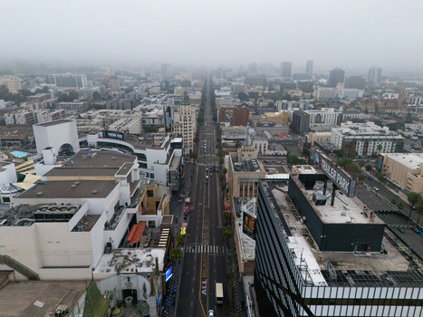 Aerial view of the Hollywood Walk of Fame featuring the iconic street lined with historic buildings and urban infrastructure under a cloudy sky in Los Angeles California United States.