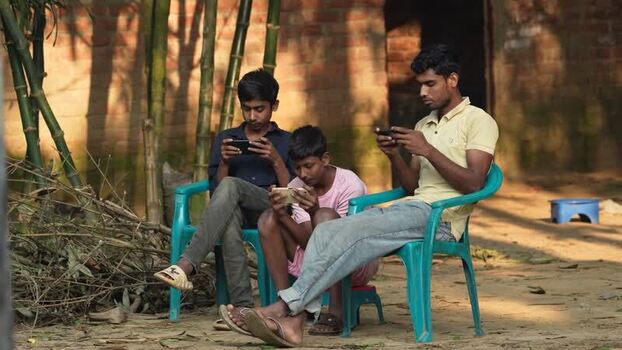 View of three young men using smartphones in Bogura Bangladesh. View of three young men using smartphones in Bogura Bangladesh.
