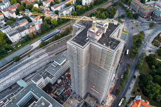 Aerial view of Steglitzer Kreisel skyscraper under renovation with scaffolding and a construction crane surrounded by urban roads and buildings in Berlin Berlin Germany. Aerial view of Steglitzer Kreisel skyscraper under renovation with scaffolding and a construction crane surrounded by urban roads and buildings in Berlin Berlin Germany.