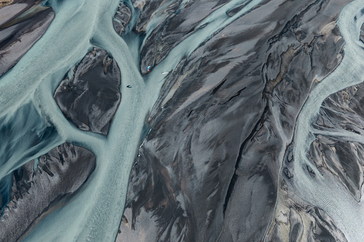 Aerial view of a braided river system with glacial water flowing through dark volcanic sand in Skaftarhreppur Iceland.