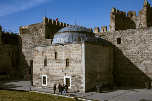 View of the historic Kayseri Castle with its ancient stone walls and a domed building in the courtyard with people walking under a clear blue sky in Kayseri Kayseri Turkiye. View of the historic Kayseri Castle with its ancient stone walls and a domed building in the courtyard with people walking under a clear blue sky in Kayseri Kayseri Turkiye.