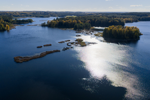 Aerial view of a serene lake with small islands and dense autumn forests under a clear blue sky in Lithuania. Aerial view of a serene lake with small islands and dense autumn forests under a clear blue sky in Lithuania.