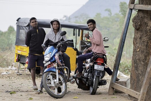 Odisha India 26 March 2026 View of three young men posing with their motorbikes near a distinctive yellow auto rickshaw against a backdrop of soft hills. Odisha India 26 March 2026 View of three young men posing with their motorbikes near a distinctive yellow auto rickshaw against a backdrop of soft hills.