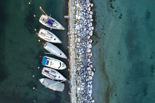 Aerial view of sailboats moored along a stone pier in the clear turquoise waters of Lake Geneva in Morges Vaud Switzerland. Aerial view of sailboats moored along a stone pier in the clear turquoise waters of Lake Geneva in Morges Vaud Switzerland.