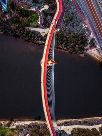 Aerial view of Boorloo Bridge spanning the Swan River with its distinctive red pedestrian path and cable stayed structure surrounded by parklands East Perth Western Australia Australia.