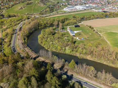 Aerial view of the Orava river curving through green landscapes with a railway and road in Nizna Zilina Region Slovakia.