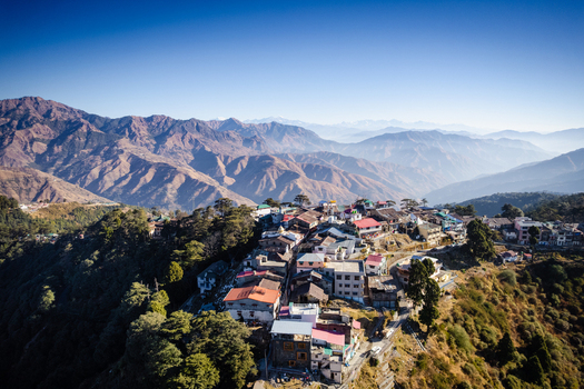 Aerial view of the hill station of Chakrata with its colorful rooftops nestled among the lush green mountains under a clear blue sky in Chakrata Uttarakhand India. Aerial view of the hill station of Chakrata with its colorful rooftops nestled among the lush green mountains under a clear blue sky in Chakrata Uttarakhand India.
