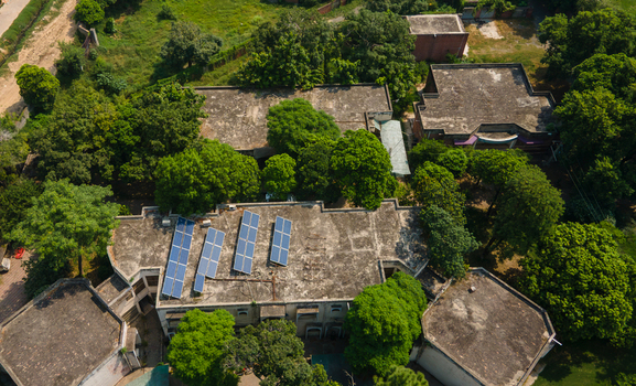 Lahore Punjab Pakistan 08 September 2026 Aerial view of a government office with solar panels on its flat roof surrounded by lush green trees in an urban setting.