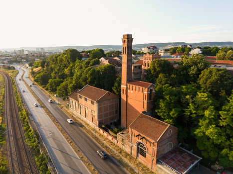 Aerial view of the historic Varna Thermal Power Plant with its iconic brick chimney surrounded by lush trees and situated next to a road and railway tracks in Varna Varna Bulgaria. Aerial view of the historic Varna Thermal Power Plant with its iconic brick chimney surrounded by lush trees and situated next to a road and railway tracks in Varna Varna Bulgaria.