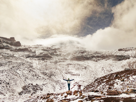 Aerial view of a person standing with arms outstretched on the snow covered slopes of Volcano Chimborazo in Guano Chimborazo Ecuador. Aerial view of a person standing with arms outstretched on the snow covered slopes of Volcano Chimborazo in Guano Chimborazo Ecuador.