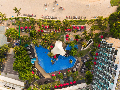 Aerial view of a luxury resort featuring a large blue swimming pool red umbrellas and lush palm trees adjacent to a sandy beach in Galle Southern Province Sri Lanka.
