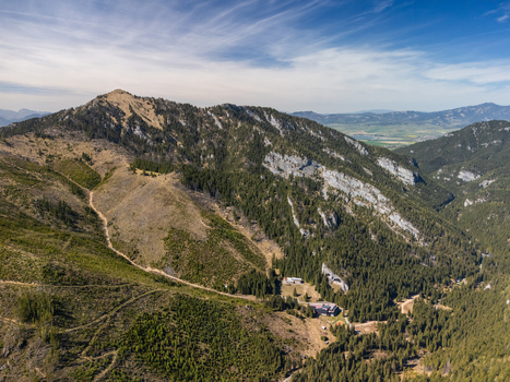 Aerial view of the Demanovska Dolina valley featuring rugged mountain peaks dense evergreen forests and rocky slopes under a bright blue sky Demanovska Dolina Zilina Region Slovakia. Aerial view of the Demanovska Dolina valley featuring rugged mountain peaks dense evergreen forests and rocky slopes under a bright blue sky Demanovska Dolina Zilina Region Slovakia.