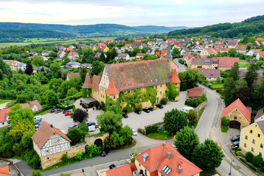 Aerial view of Schloss Wiesenthau with its ivy covered walls and red tiled towers surrounded by the village and green hills Wiesenthau Bayern Germany. Aerial view of Schloss Wiesenthau with its ivy covered walls and red tiled towers surrounded by the village and green hills Wiesenthau Bayern Germany.
