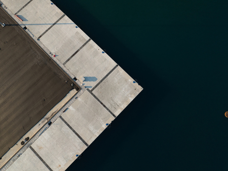 Aerial view of the geometric corner of a concrete industrial pier meeting the deep blue sea water Augusta Sicily Italy. Aerial view of the geometric corner of a concrete industrial pier meeting the deep blue sea water Augusta Sicily Italy.