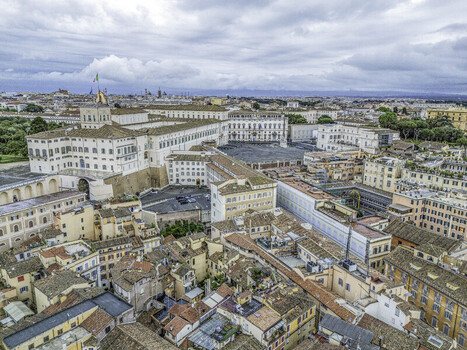 Aerial view of the Quirinal Palace and surrounding historic rooftops under a cloudy sky in Rome Italy.