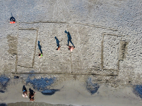 Aerial view of a soccer field outline drawn in the sand with people walking on the beach in San Lorenzo Liguria Italy.