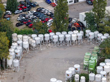 Berlin Germany 26 September 2026 Aerial view of Caparol Berlin facility with numerous white and green industrial silos arranged in a yard adjacent to a parking lot filled with cars.