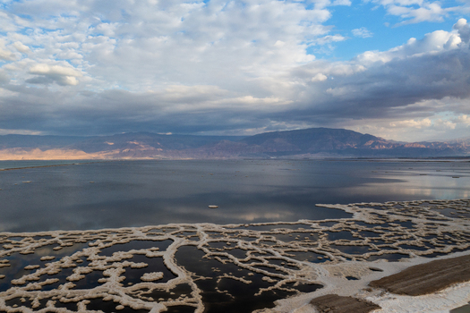 Aerial view of the Dead Sea s waters reflecting the cloudy sky and surrounding desert landscape the salt formations contrasting with the dark water Arad South District Israel. Aerial view of the Dead Sea s waters reflecting the cloudy sky and surrounding desert landscape the salt formations contrasting with the dark water Arad South District Israel.