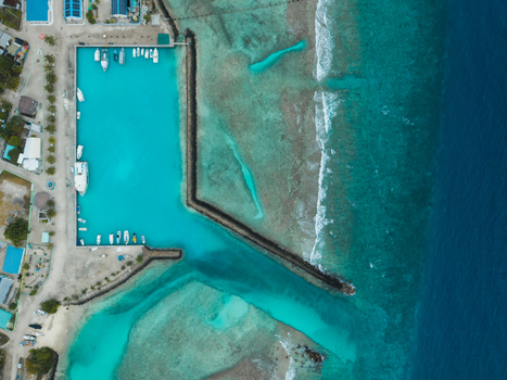 Aerial view of boats nestled in the turquoise harbour contrasting with the deep blue sea Vashafaru Island Thiladhummathi Atoll Maldives. Aerial view of boats nestled in the turquoise harbour contrasting with the deep blue sea Vashafaru Island Thiladhummathi Atoll Maldives.