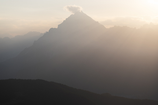View of Dolomites mountain peaks shrouded in golden mist and sun rays during sunset Trentino Alto Adige Italy. View of Dolomites mountain peaks shrouded in golden mist and sun rays during sunset Trentino Alto Adige Italy.