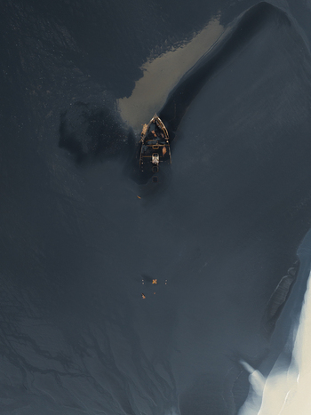 Aerial view of a lone boat adrift on the glacial lagoon s inky waters a stark contrast to the icy shorelines Skaftafell Iceland. Aerial view of a lone boat adrift on the glacial lagoon s inky waters a stark contrast to the icy shorelines Skaftafell Iceland.