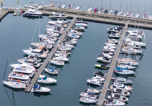 Aerial view of the marina in Sopot featuring numerous yachts and sailboats docked in orderly rows along wooden piers surrounded by calm harbor water in Sopot Pomeranian Voivodeship Poland. Aerial view of the marina in Sopot featuring numerous yachts and sailboats docked in orderly rows along wooden piers surrounded by calm harbor water in Sopot Pomeranian Voivodeship Poland.