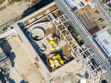 Aerial view of an Hospital construction site featuring circular structures and yellow insulation materials on a flat roof with scaffolding in Ancona Marche Italy. Aerial view of an Hospital construction site featuring circular structures and yellow insulation materials on a flat roof with scaffolding in Ancona Marche Italy.