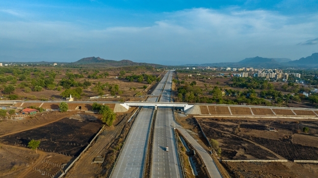Aerial view of JNPT Highway Badlapur tunnel featuring a modern bridge structure spanning across dry landscape with distant hills under a clear blue sky in Badlapur Maharashtra India. Aerial view of JNPT Highway Badlapur tunnel featuring a modern bridge structure spanning across dry landscape with distant hills under a clear blue sky in Badlapur Maharashtra India.