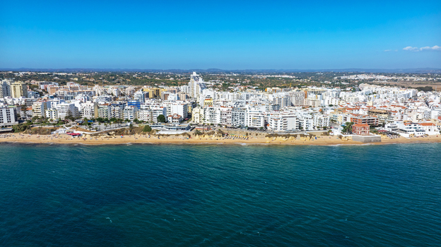 Aerial view of the coastal town of Armacao de Pera with its sandy beach white buildings and blue sea in Armacao de Pera Faro District Portugal. Aerial view of the coastal town of Armacao de Pera with its sandy beach white buildings and blue sea in Armacao de Pera Faro District Portugal.
