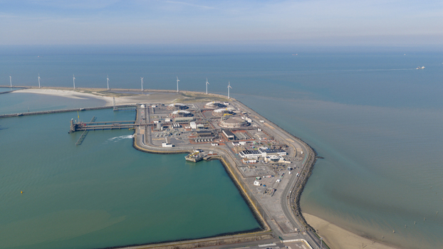 Aerial view of the Fluxys LNG Terminal Zeebrugge featuring industrial storage tanks and coastal wind turbines along the North Sea in Brugge Vlaanderen Belgium. Aerial view of the Fluxys LNG Terminal Zeebrugge featuring industrial storage tanks and coastal wind turbines along the North Sea in Brugge Vlaanderen Belgium.