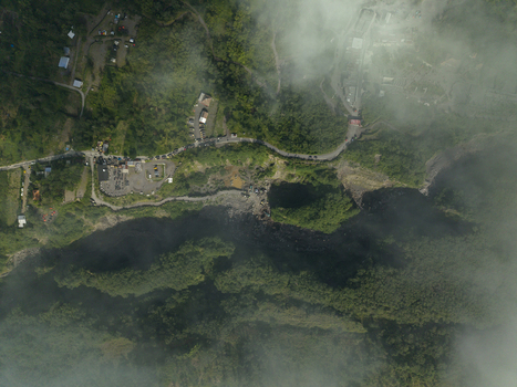 Aerial view of Tambang Pasir Merapi Kali Gendol Sand Mine with a deep ravine lush vegetation and a winding road in Kecamatan Cangkringan Daerah Istimewa Yogyakarta Indonesia. Aerial view of Tambang Pasir Merapi Kali Gendol Sand Mine with a deep ravine lush vegetation and a winding road in Kecamatan Cangkringan Daerah Istimewa Yogyakarta Indonesia.