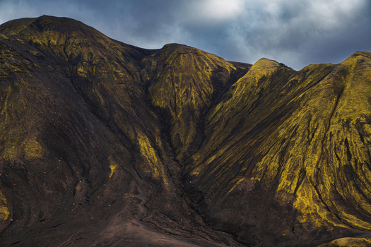 View of stark dark mountains contrasting vivid green moss under a cloudy sky a rugged landscape embodying Iceland s raw beauty Skaftárhreppur Iceland. View of stark dark mountains contrasting vivid green moss under a cloudy sky a rugged landscape embodying Iceland s raw beauty Skaftárhreppur Iceland.