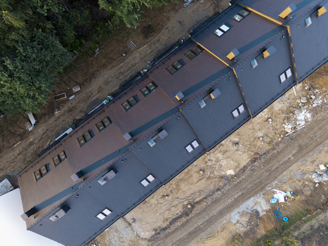 Aerial view of modern terraced houses under construction with dark tiled roofs and skylights situated in a residential development area in Wieliczka Lesser Poland Voivode Poland.