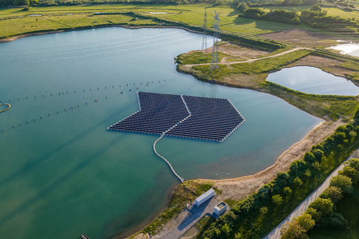 Aerial view of floating solar plant on a lake surrounded by green fields and power lines in Bensheim Hessen Germany. Aerial view of floating solar plant on a lake surrounded by green fields and power lines in Bensheim Hessen Germany.