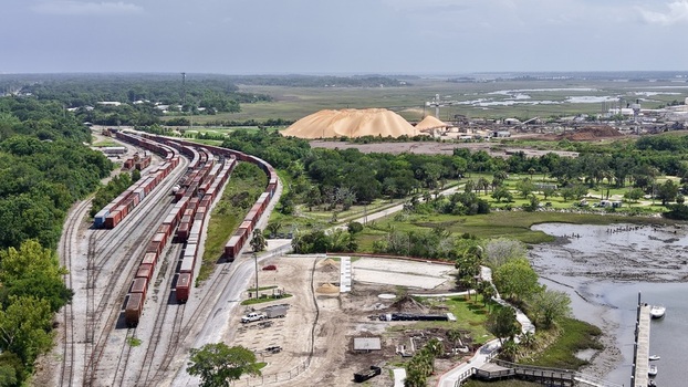 Aerial view of a railway yard with freight cars green forests a golden industrial pile and a calm estuary Fernandina Beach Florida United States. Aerial view of a railway yard with freight cars green forests a golden industrial pile and a calm estuary Fernandina Beach Florida United States.