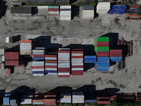 Aerial view of colorful shipping containers stacked in an industrial yard with long shadows on the asphalt ground in Cincinnati OH United States.