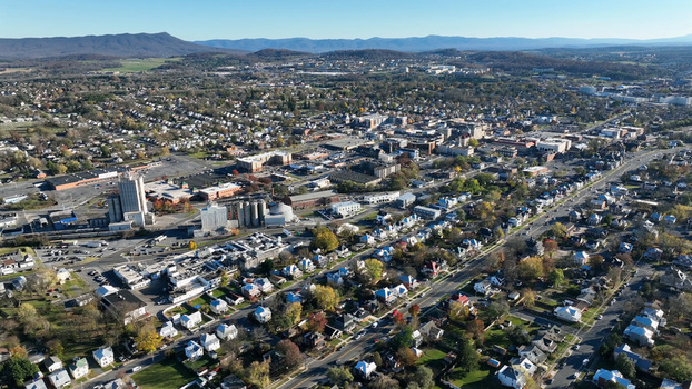 Aerial view of Harrisonburg featuring residential neighborhoods commercial buildings and industrial structures set against rolling hills in Harrisonburg Virginia United States.