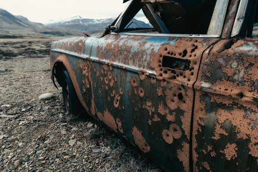 View of a rusted bullet riddled vintage car abandoned in the desolate landscape of Stokksnes Iceland.