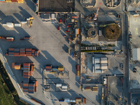 Aerial view of an industrial port area with stacked shipping containers heavy machinery and large cable reels under low sunlight in Augusta Sicily Italy. Aerial view of an industrial port area with stacked shipping containers heavy machinery and large cable reels under low sunlight in Augusta Sicily Italy.