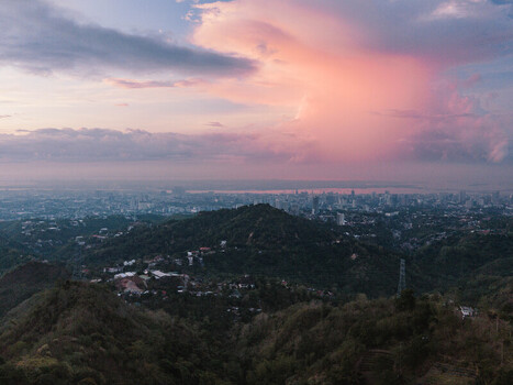 Cebu City Philippines 20 May 2026 Aerial view of the urban skyline and lush hills of Busay under a vibrant pink sunset sky.
