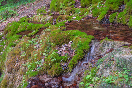 View of the Pancierovske travertines featuring a small waterfall flowing over moss covered rocks in Banska Bystrica Banskobystricky kraj Slovakia. View of the Pancierovske travertines featuring a small waterfall flowing over moss covered rocks in Banska Bystrica Banskobystricky kraj Slovakia.