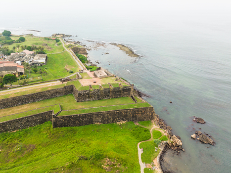 Aerial view of Galle Fort with its historic stone ramparts lush green lawns and rocky coastline under a hazy sky in Galle Southern Province Sri Lanka. Aerial view of Galle Fort with its historic stone ramparts lush green lawns and rocky coastline under a hazy sky in Galle Southern Province Sri Lanka.