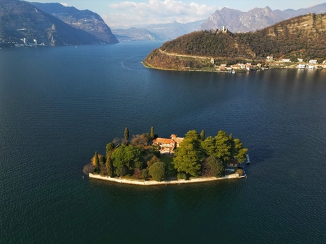 Aerial view of the historic villa on Isola di Loreto surrounded by lush trees on Lake Iseo with Monte Isola in the background Monte Isola Lombardy Italy. Aerial view of the historic villa on Isola di Loreto surrounded by lush trees on Lake Iseo with Monte Isola in the background Monte Isola Lombardy Italy.