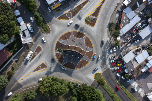 Aerial view of a roundabout with landscaped garden beds surrounding streets with light traffic and urban buildings in Uruapan Michoacan Mexico. Aerial view of a roundabout with landscaped garden beds surrounding streets with light traffic and urban buildings in Uruapan Michoacan Mexico.