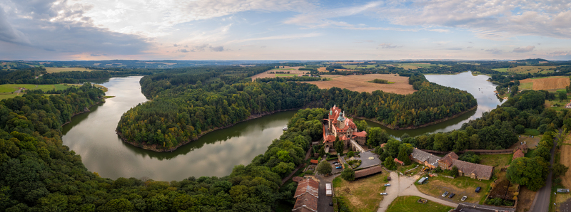Aerial view of Czocha Castle situated on a forested peninsula surrounded by a winding river under a cloudy sky in Sucha Lower Silesian Voivodeship Poland. Aerial view of Czocha Castle situated on a forested peninsula surrounded by a winding river under a cloudy sky in Sucha Lower Silesian Voivodeship Poland.