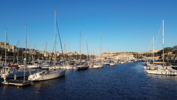 Aerial view of numerous sailboats and yachts moored in the marina with historic stone buildings and fortifications visible along the waterfront in Valletta Port Region Malta. Aerial view of numerous sailboats and yachts moored in the marina with historic stone buildings and fortifications visible along the waterfront in Valletta Port Region Malta.